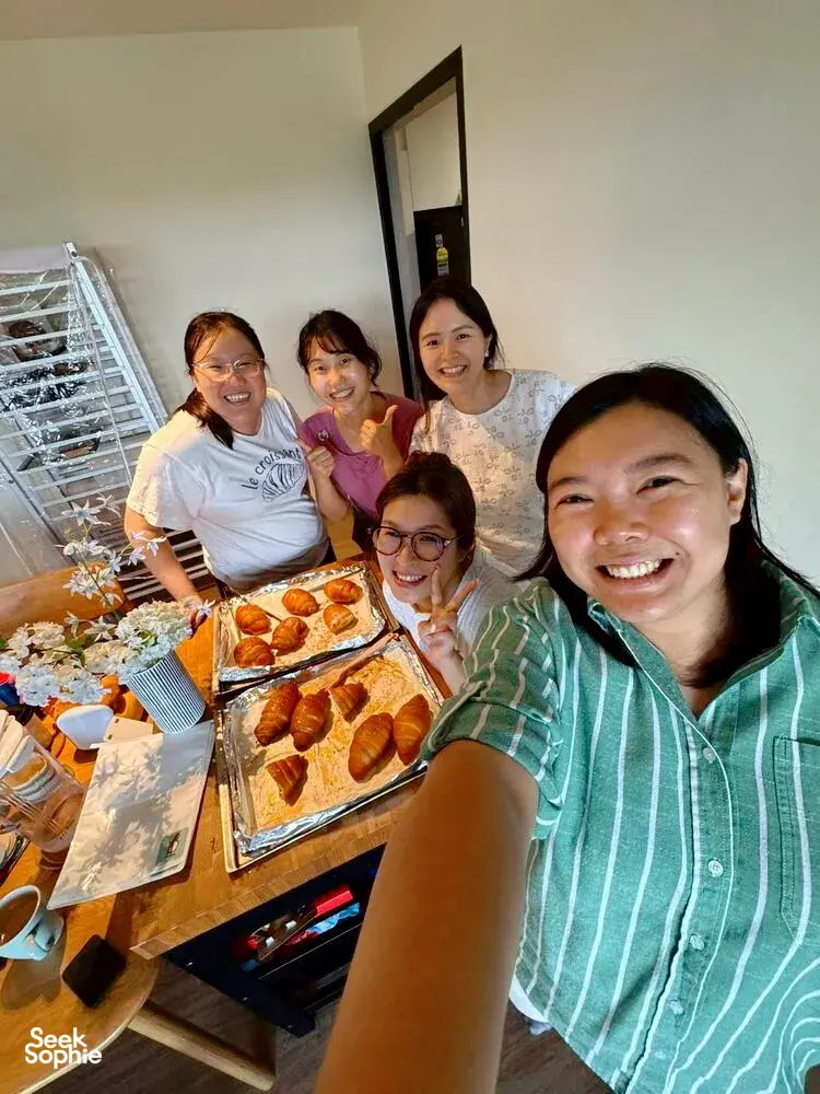 Smiling group posing at a kitchen table with trays of baked shio pan after flavoured butter making with The Daily Staples in Singapore