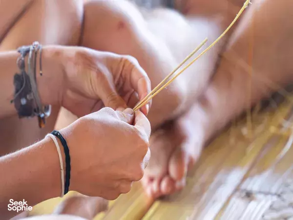 Close-up of hands tying thin bamboo strands with string during Bamboo Creative Bali’s bamboo building workshop in Bali