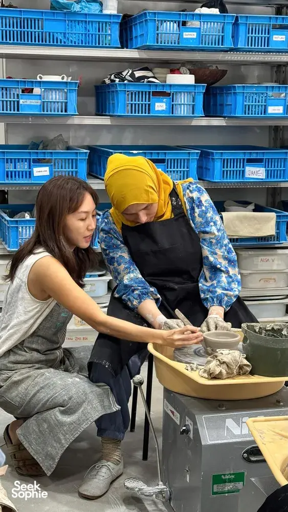 Student in a yellow headscarf shaping clay on a pottery wheel at the 3Arts Pottery studio in Singapore — workshops in Singapore