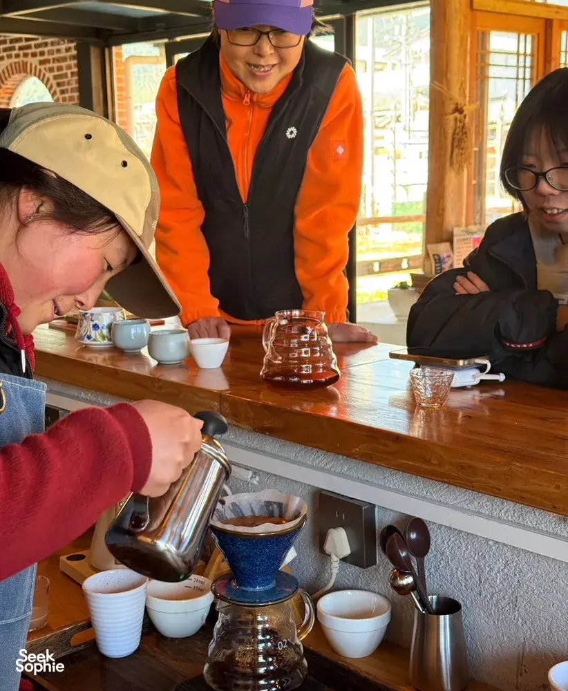 Tasting session at a coffee workshop in Lijiang as guests pour and brew Yunnan specialty coffee from a glass siphon brewer