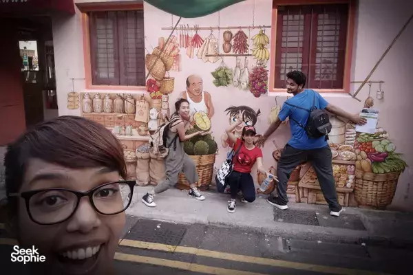Participants pose outside a colourful shopfront mural during a sustainable outdoor scavenger hunt in Singapore