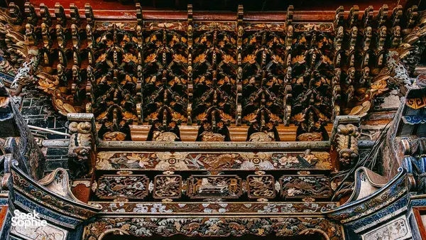 Decorative temple-style roof beams and painted carvings inside an old hall in Xizhou Old Town, Dali