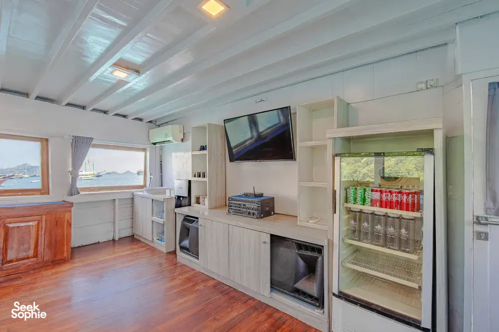 Onboard bar and kitchenette with a glass-door fridge, microwave and TV, for drinks on a 3-day join-in Komodo boat trip in Labuan Bajo