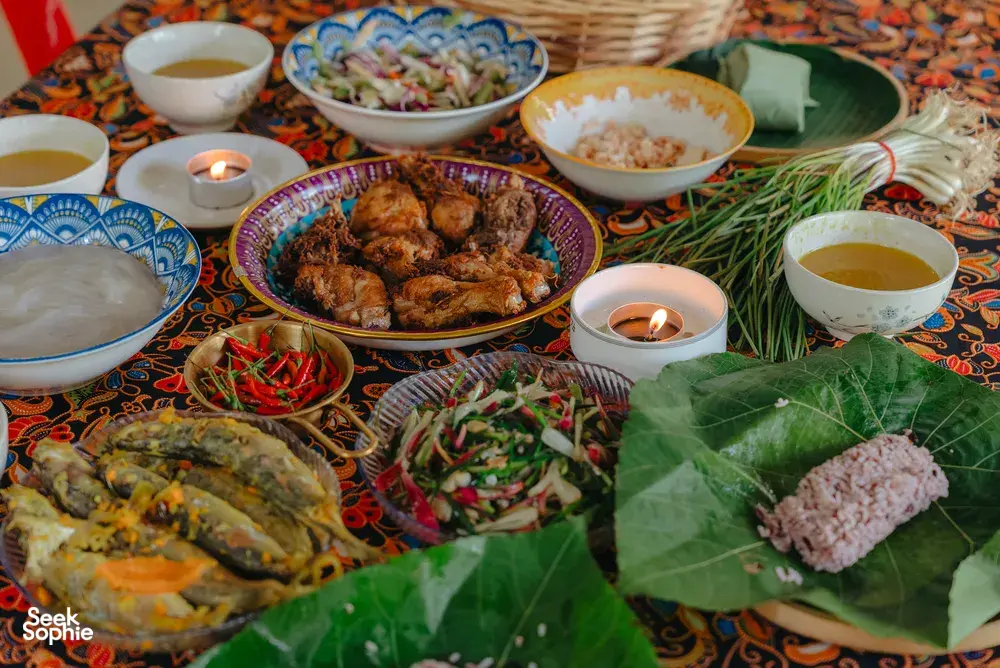 Kota Kinabalu Indigenous Sabahan cooking feast spread with grilled meat, herbs and steaming bowls on a patterned table