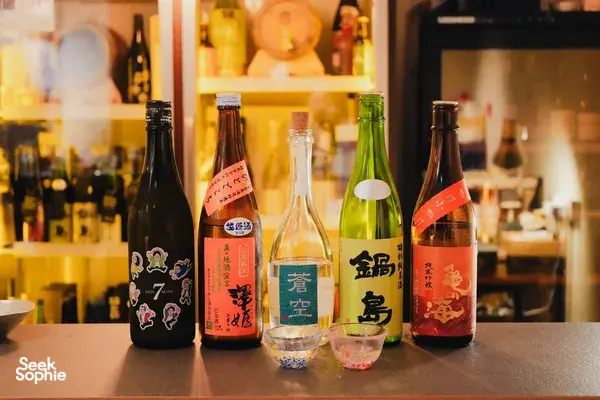 Assorted rare sake bottles and tasting glasses arranged on the counter in a Singapore shop, ready for a guided pour