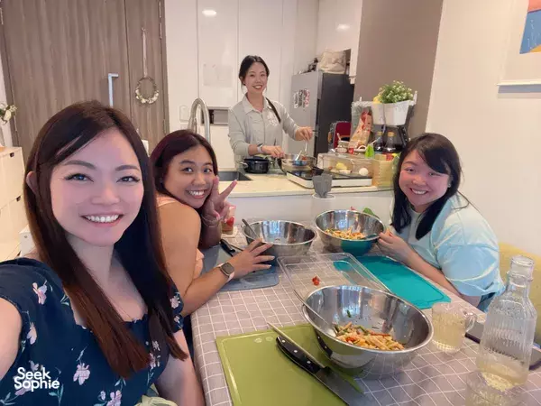 Diners seated at a Singapore cooking table with bowls of ingredients while a Korean chef demonstrates kimchi-making