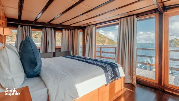 Deluxe phinisi cabin with a double bed and sea-view windows on a 4D3N shared Komodo cruise, Komodo Island