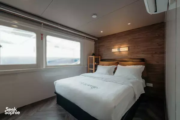 MS Eternity twin-deck catamaran cabin in Singapore, with a made-up double bed, pillows and large side windows