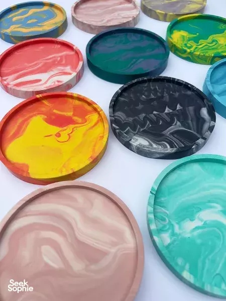 Swirled Jesmonite coasters in pink, teal, green, yellow and black on a table for make-your-own workshops in Singapore