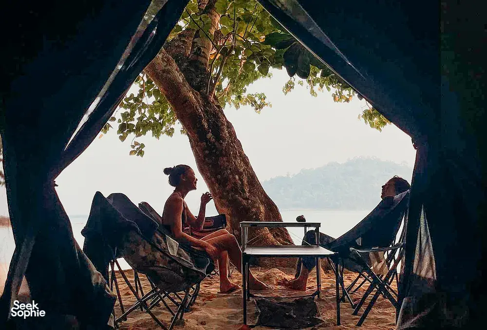 Relaxing under a shaded beach shelter with loungers and a table, overlooking trees and sea at Surin Island, Khao Lak