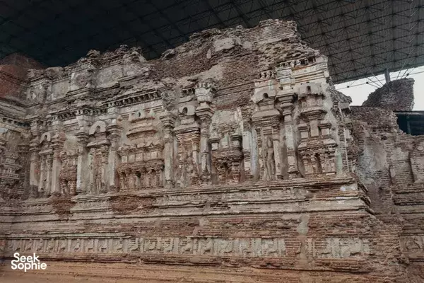 Weathered temple reliefs covering a stone wall inside a covered ruin in Polonnaruwa’s ancient complex