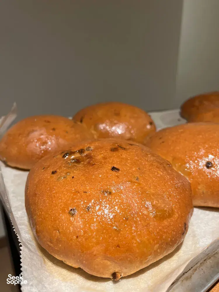 Glazed golden bread rolls with dark herb pieces on parchment at The Daily Staples baking class in Singapore — workshops in Singapore