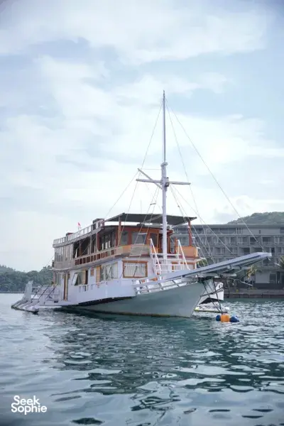 Wooden liveaboard sailing boat with rigging moored on calm water for a 3D2N join-in Komodo trip in Labuan Bajo