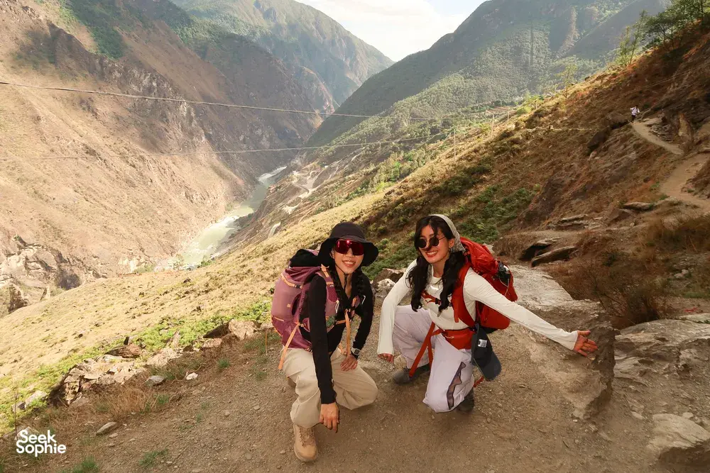 Backpackers hiking along a dirt trail with wide valley views in Tiger Leaping Gorge, Lijiang, on the 2D1N high trail