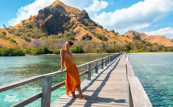 Travellers on a phinisi deck with turquoise water and rugged hills during a 4D3N trip from Labuan Bajo on Komodo Island
