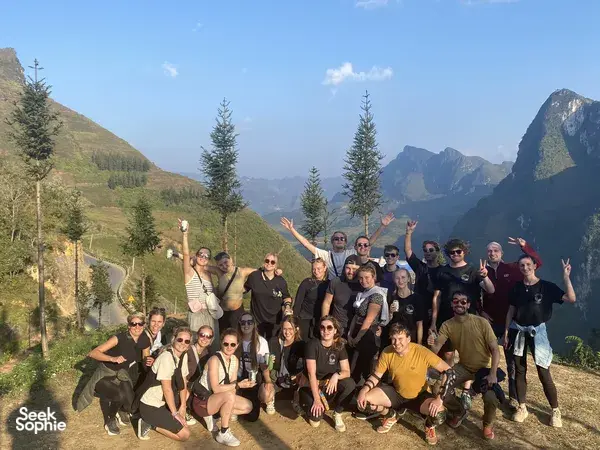 Travellers posing on a mountain ridge with greenery valleys behind them in Ha Giang during the Ha Giang loop