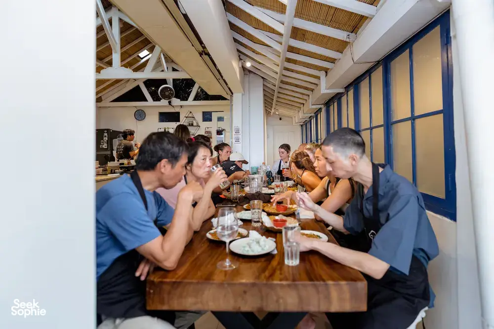 Gili Islands cooking class in Lombok: group dining at a long table, enjoying the dishes they've just learnt to cook