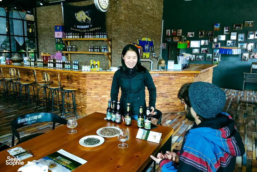 Beer tasting in a rustic bar in Shangri-La, with glasses on a table as a guide presents bottled brews to guests