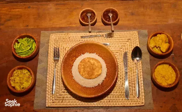 Breakfast table set with bowls of vegetables and curry on woven placemats at The Elephant Next Door restaurant in Udawalawe