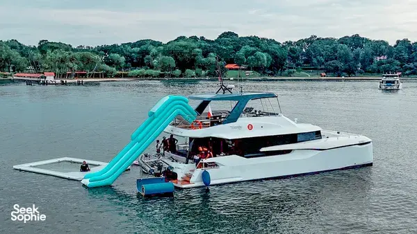 MS Eternity catamaran moored on a calm Singapore waterway with bright blue inflatable slide, ready for a 4-hour Lazarus cruise