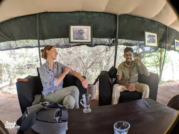 Guests relaxing in a Leopard Trails safari tent lounge, with a table in front and framed safari art on the walls