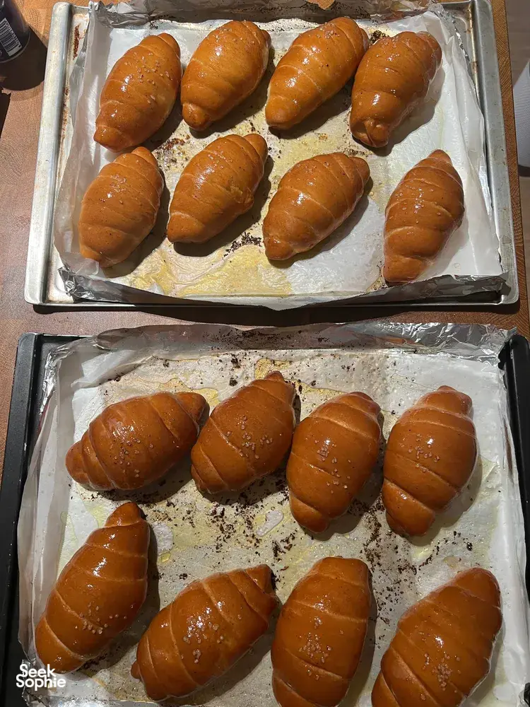 Glazed shio pan rolls filling two parchment-lined trays as they cool after baking during workshops in Singapore