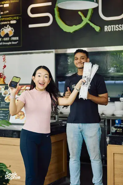 Participants in a real-life Monopoly game at a Singapore River restaurant counter, holding vouchers and menus—Singapore hidden gems