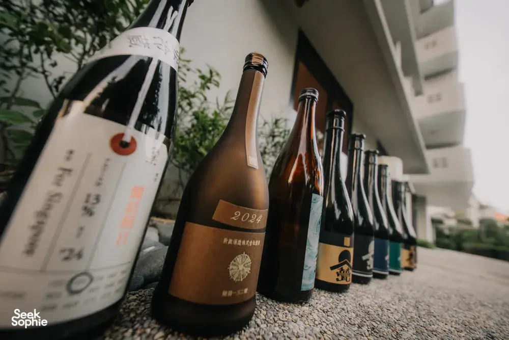 Line of labelled sake bottles for a rare Singapore tasting, housed along a corridor display in a tucked-away shop