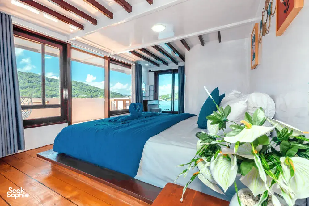 Double cabin bed with folded linens and a flower arrangement on a sleek phinisi during La Famille’s private 3D2N Komodo cruise in Labuan Bajo