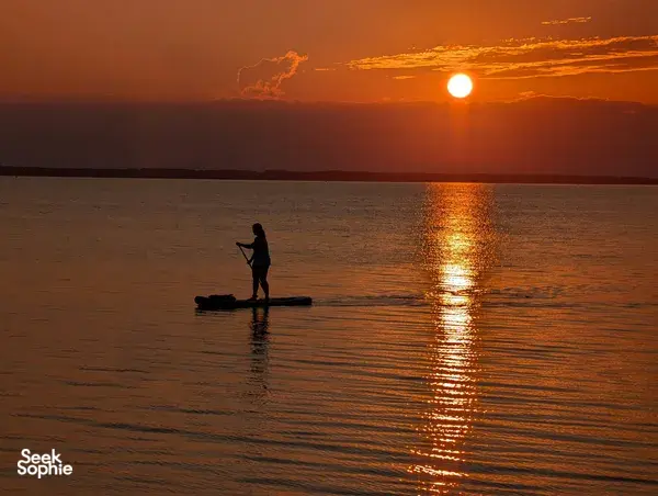 Paddleboarder with Xtreme Paddlers at sunrise over Tanjung Aru beach in calm water, Kota Kinabalu, Sabah