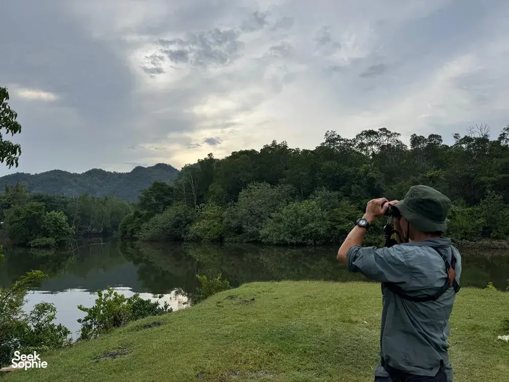 Wendy Nature Guide photographing wildlife by a calm river in Langkawi, on an outdoor birdwatching and nature-spotting walk