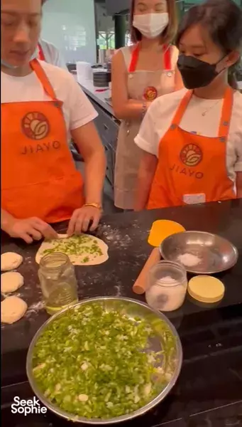 Masked participants at a Taiwanese cooking class in Singapore mix ingredients in pans, guided over a worktop — workshops in Singapore