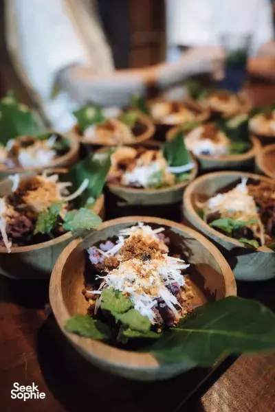 Assorted starters in small wooden bowls with shredded toppings and green leaves, set on a dinner table in Labuan Bajo