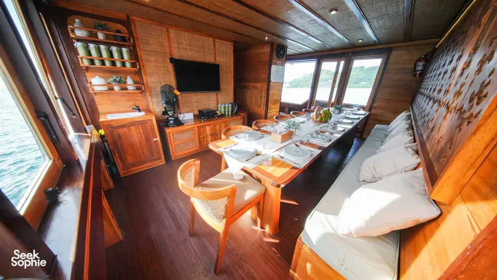 Dining table set on a wooden phinisi lounge for onboard meals during the 3D2N Komodo cruise in Labuan Bajo