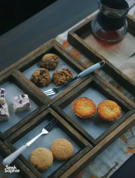 Selection of bite-size pastries and cookies beside multiple cups of brewed coffee on a wooden serving tray at Seeker Yunnan Coffee Estate