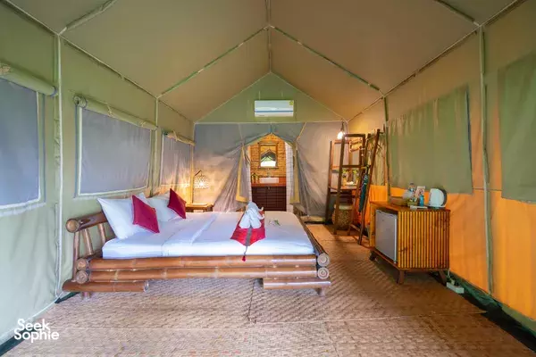 Cozy luxury glamping tent interior in Khao Sok with a bamboo bed and cosy seating, prepared for a Cheow Lan Lake day trip