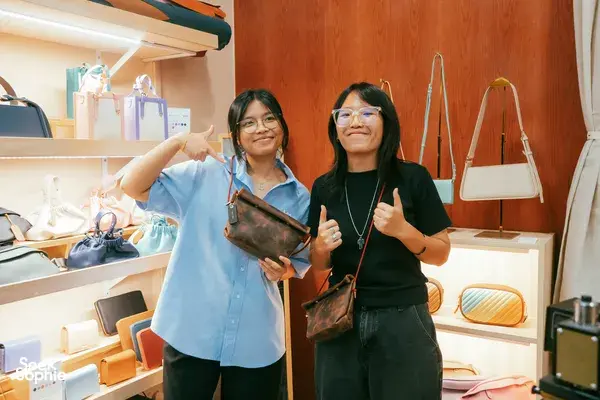 Two participants at Crafune in New Bahru, Singapore, holding finished leather bags and smiling with thumbs up during workshops in Singapore