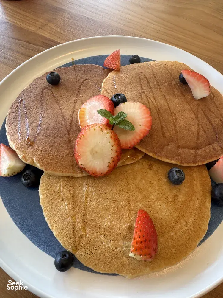Pancake keemasan terinspirasi TCM dengan stroberi, blueberry, dan mint di atas piring biru, bagian dari lokakarya Food as Medicine di Singapura