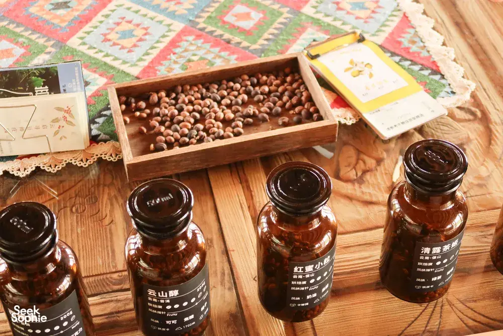 Tray of coffee beans above wooden shelves of labelled jars at Seeker Yunnan Coffee Estate in Lijiang