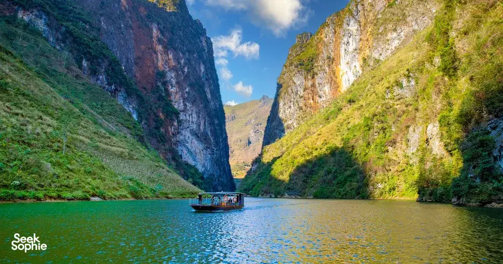 在妈妈带领的河江环线风景之旅中，一艘小船漂浮在平静的湖面上，两侧是高耸的喀斯特悬崖