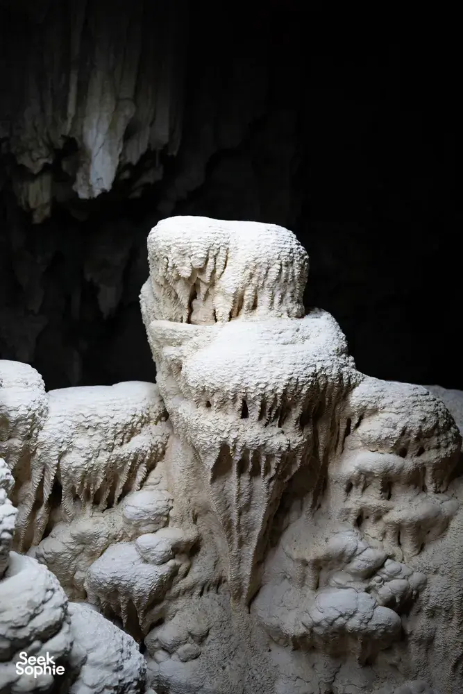 Carved stone statue surrounded by rough limestone in a dark cave on a Khao Sok journey in Khao Sok National Park