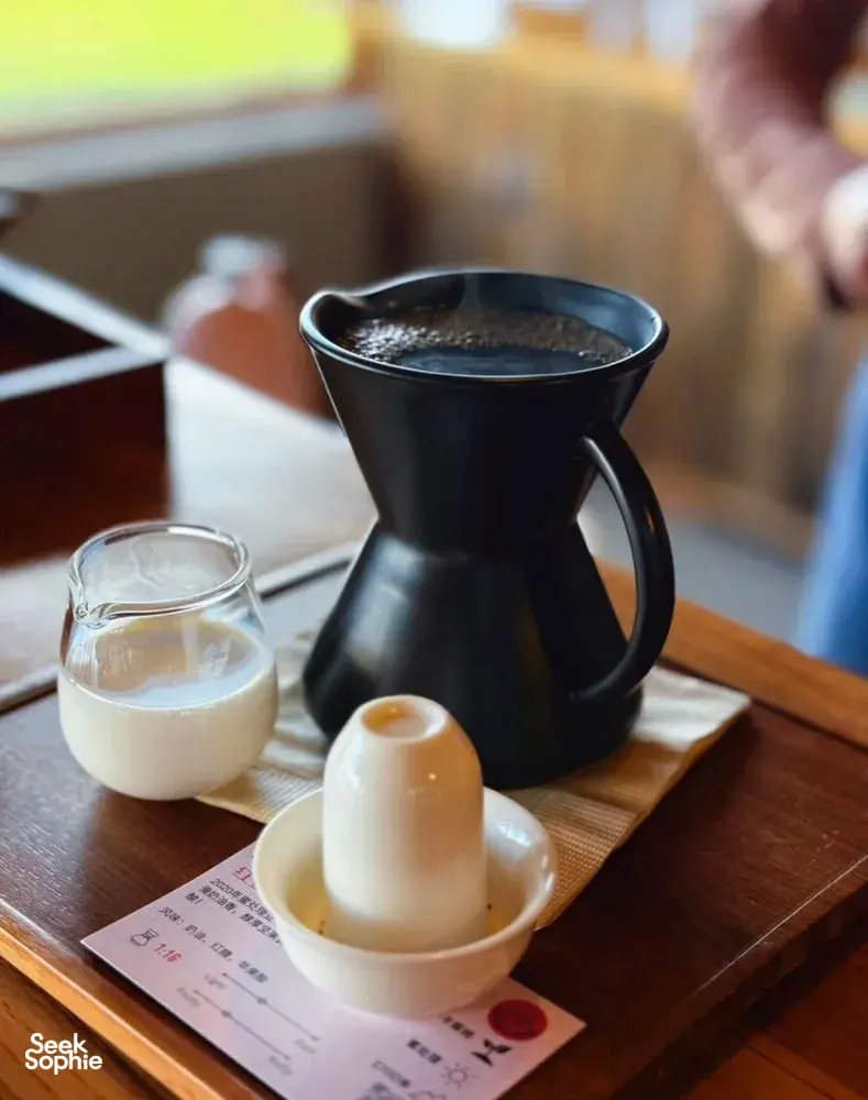 Black pour-over coffee setup with small glass tasting cups on a tray at Seeker Yunnan Coffee Estate workshop in Lijiang