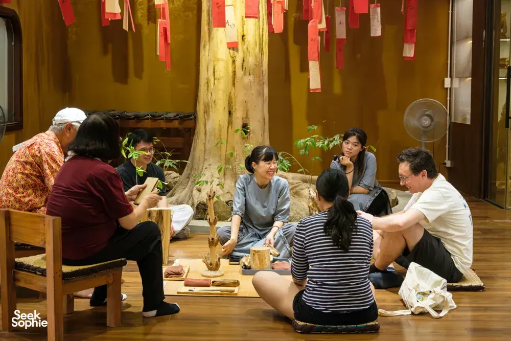 Small group tasting and learning at a wooden table as a host guides an agarwood scent workshop in Hanoi