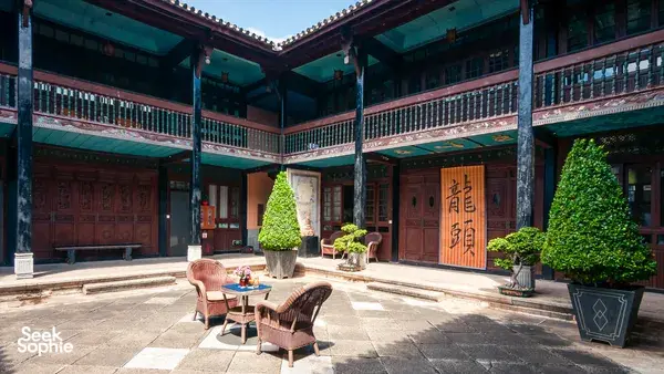 Courtyard of a restored Bai home at Linden Centre in Xizhou Old Town, Dali, with wooden balconies, greenery and outdoor seating