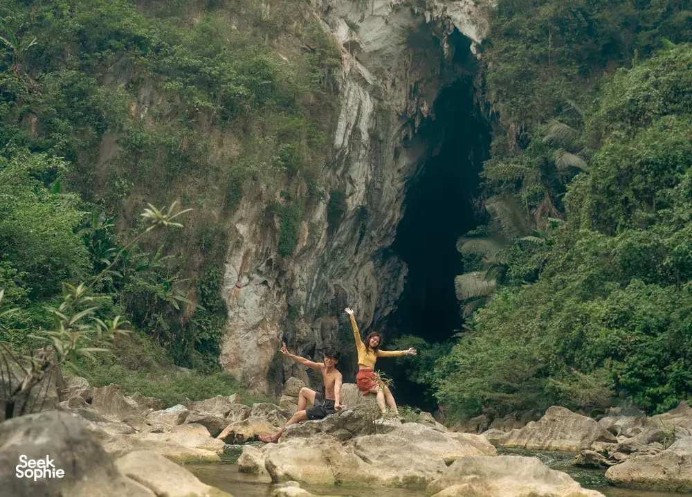 Travellers in Phong Nha’s limestone cliffs and jungle landscape, arms out on a rocky trail during a Greenland Tours outing