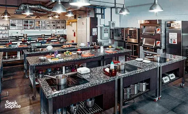 Professional teaching kitchen in Singapore with rows of granite stations, ovens and prep equipment for hands-on baking workshops in Singapore