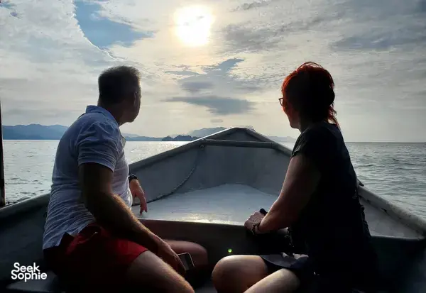 Silhouette of two passengers on a small boat at sunset over the Andaman Sea in Langkawi during a mangrove cruise