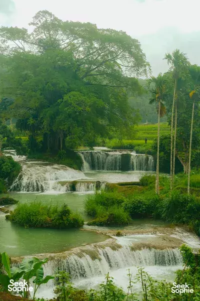 Lush jungle waterfall tumbling over terraces, misty green surroundings for an easy day trip around West Sumba