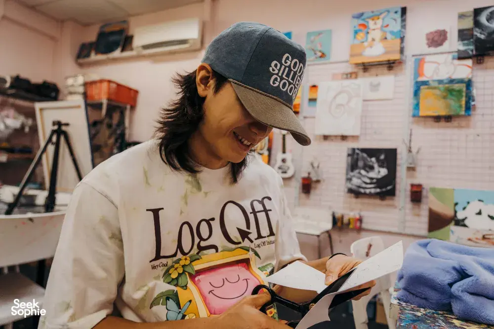 Smiling instructor sketching a plushie keychain at Avant-Garde Art Space in Singapore with art supplies — workshops in Singapore