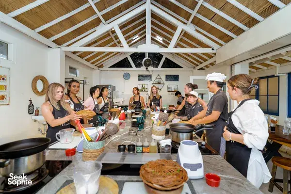 Small group Indonesian cooking class on Gili T in Lombok gathered around pots and utensils under a high white ceiling